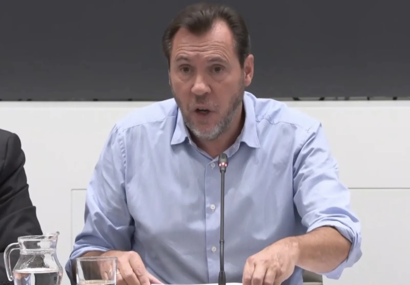Óscar Puente, con camisa azul, habla ante un micrófono en la rueda de prensa sobre el accidente de Urda en el Ministerio de Transportes.
